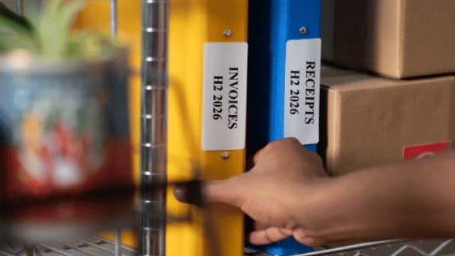 Hand holding yellow invoice folder on shelf