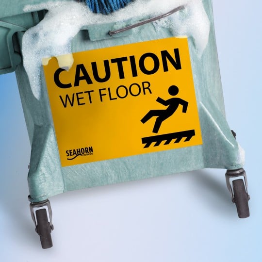 Yellow sign Cation Wet Floor on a mop bucket