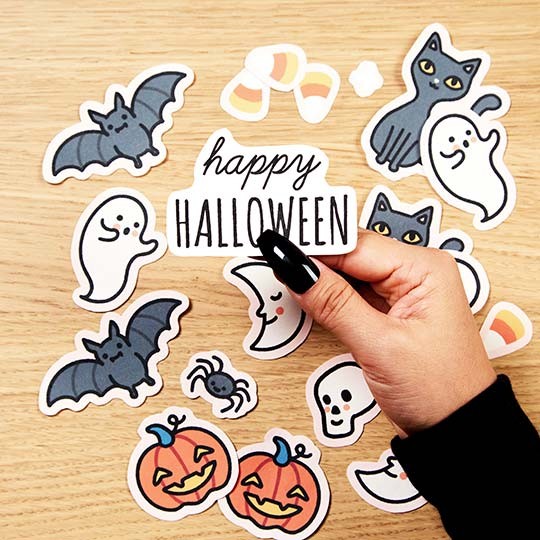 Hand holding a sticker with Happy Halloween