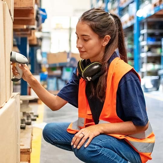Industrial woman scanning box in warehouse