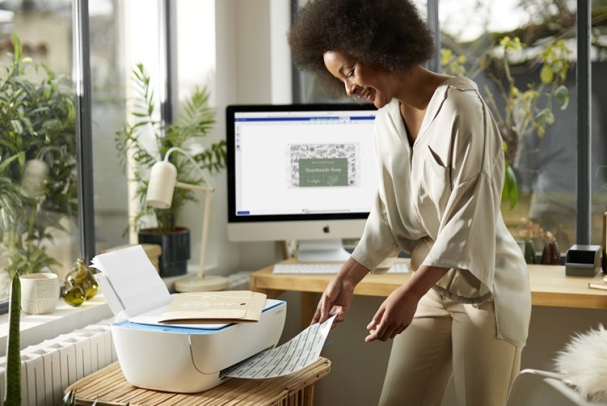 Woman at printer collecting sheet of labels