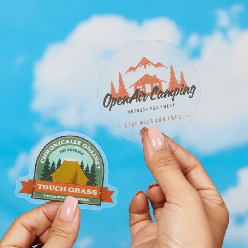 Fingers holding clear stickers with sky background