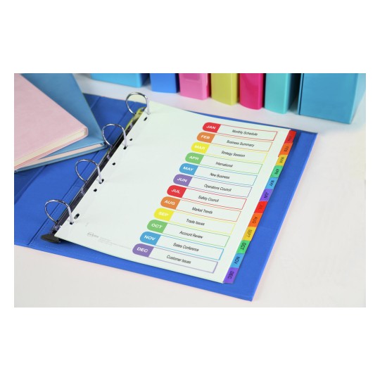 The image features an organized binder showing a monthly schedule with tabs for each month. The schedule lists various topics such as Business Summary, Market Trends, and Customer Issues. Surrounding the binder are colorful notebooks and binders.