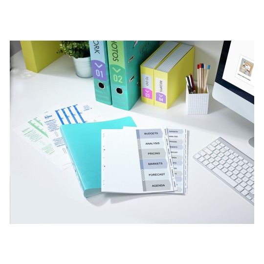The image depicts an organized workspace with binders, folders, and labeled tabs for budgets, analysis, pricing, markets, forecast, and agenda. There are also printed documents and a computer keyboard visible.