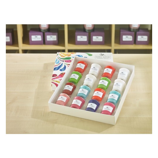 The image shows a box of colorful candles arranged neatly. The box is designed with a floral pattern and contains a variety of candles in different colors, labeled 'Floral Nature'. The background features more candles on display, highlighting a cozy, aromatic atmosphere.