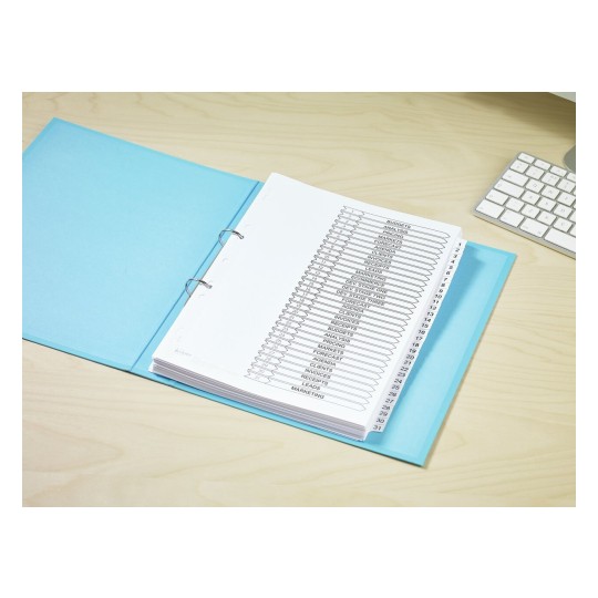 The image shows a blue binder open on a wooden desk. Inside, there are white pages with organized labeled tabs indicating various categories such as budgets, analysis, and marketing. A computer keyboard is also visible in the background.