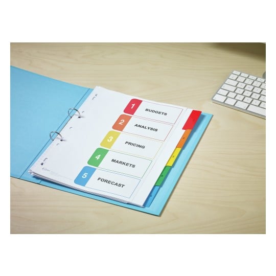 The image shows a blue folder containing a binder with labeled sections for budgets, analysis, pricing, markets, and forecast. A keyboard is visible in the background on a wooden desk.