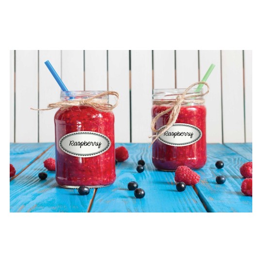 The image features two jars filled with raspberry jam, each labeled 'Raspberry'. One jar has a blue straw, while the other has a green straw. They are placed on a vibrant blue wooden surface, surrounded by fresh raspberries and blueberries.