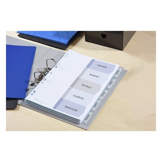 The image shows a binder with tabbed sections labeled 'Agenda', 'Budget', 'Details', 'Clients', and 'Services', alongside some blue folders and a black box on a wooden surface.