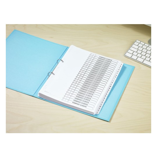 The image shows a neatly organized binder with tabs labeled 'Company Clients' arranged alphabetically. The binder has a blue cover and is placed on a wooden desk next to a computer keyboard.