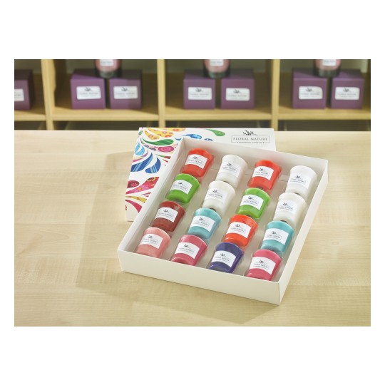 The image features a neatly arranged box containing colorful candles of various shapes and sizes. Each candle has a label with the brand name 'Floral Nature.' The background showcases additional candles and decorative boxes.