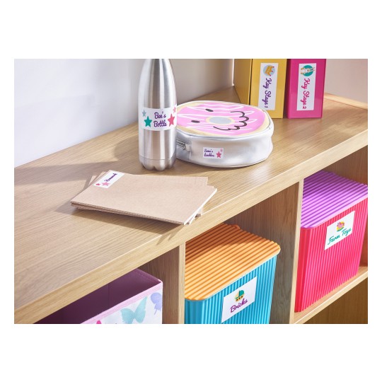 The image showcases a tidy shelf with various labeled items. There's a stainless steel water bottle, a lunchbox with a donut design, a stack of notebooks, and colorful storage bins labeled for different categories such as toys and bricks, all placed on a wooden surface.