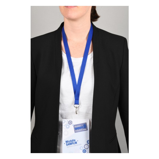 The image shows a person wearing a black blazer, standing against a grey background. They are displaying a name badge with blue lanyard. The badge includes the name 'Michèle SAMPLIN' and is associated with an industry group meeting.
