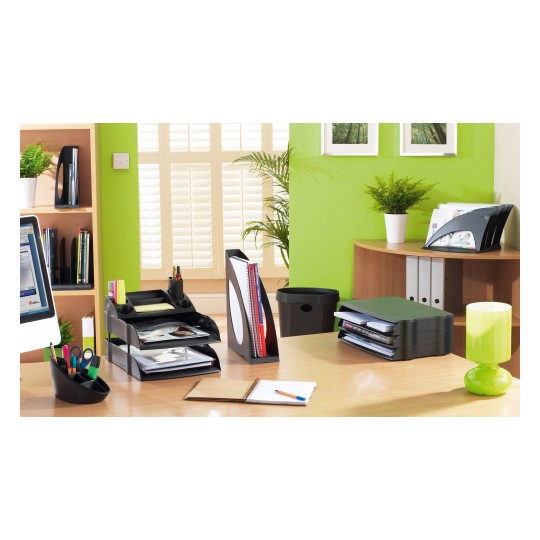 The image shows a modern office space with a green wall, a desk equipped with a computer, stationery holders, stacked documents, a notebook, and decorative plants.