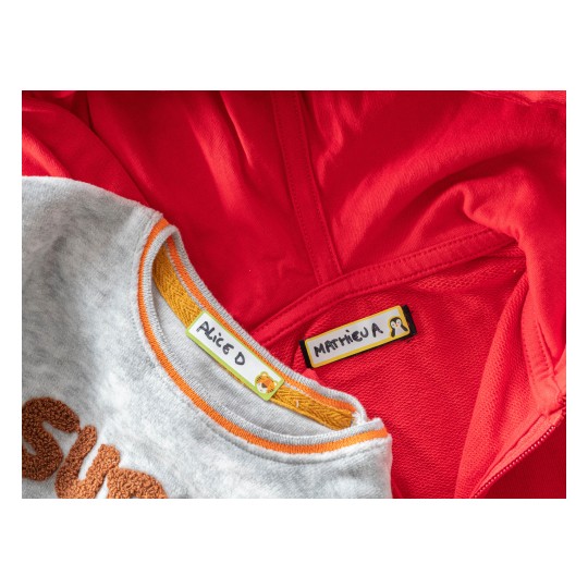 The image shows two clothing items: a gray sweatshirt with the name tag 'Alice D' and a red jacket with the name tag 'Mathieu A'.
