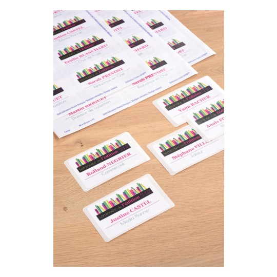 The image shows name badges with names and professional titles on a wooden surface, featuring a colorful design with books.