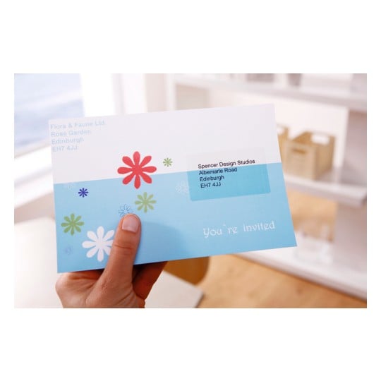 An invitation card held in a hand, featuring colorful floral designs and the text 'You're invited.' The card has an address label for Spencer Design Studios in Edinburgh.