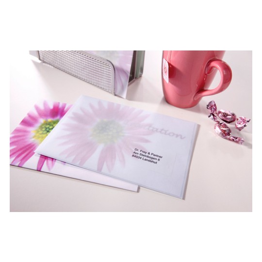 The image shows two envelopes with a floral design, a pink mug, a metal holder, and some candies on a table.