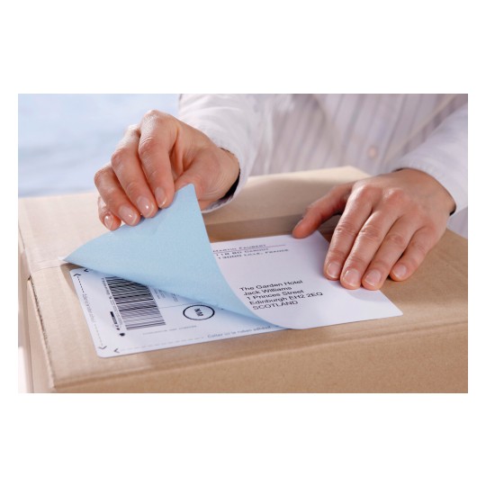 A person removing a label from a package. The package is brown and the label contains an address of a hotel in Scotland.
