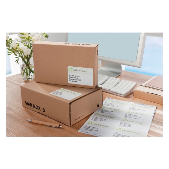 The image shows gifts in brown boxes with shipping labels, a pen and a computer on a desk with a vase of flowers in the background.