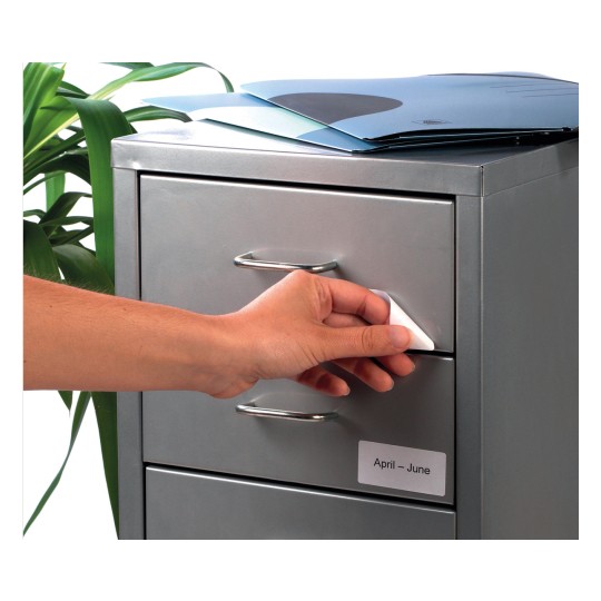 In the image, a hand is seen opening a drawer of a gray cabinet. The cabinet has a label indicating 'April - June' and there are some folders on top. A plant is visible on the side.