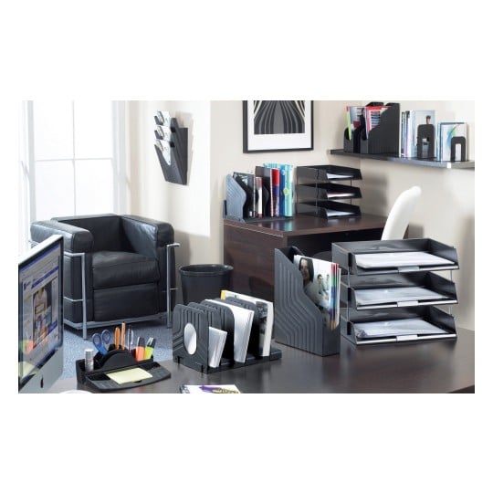The image shows a modern office space with a black leather chair, a desk organized with various filing and stationery supplies, and a window letting in natural light. Items include magazine holders, document trays, pens, and a computer monitor displaying a webpage.