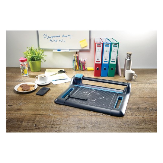In the image, a desk can be seen with a paper cutter, a cup of coffee, cookies on a plate, a mobile phone, a water bottle, writing tools, and document organizers in various colors, along with a decorative plant.