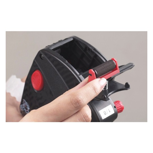 This is an image of a hand holding a black device with a red button and a roller being removed from it. The device seems to be some sort of tape dispenser or label maker.