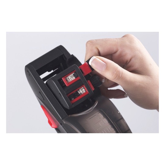 The image shows a hand holding and adjusting a price indicator. The device has a digital and mechanical display with numbers.