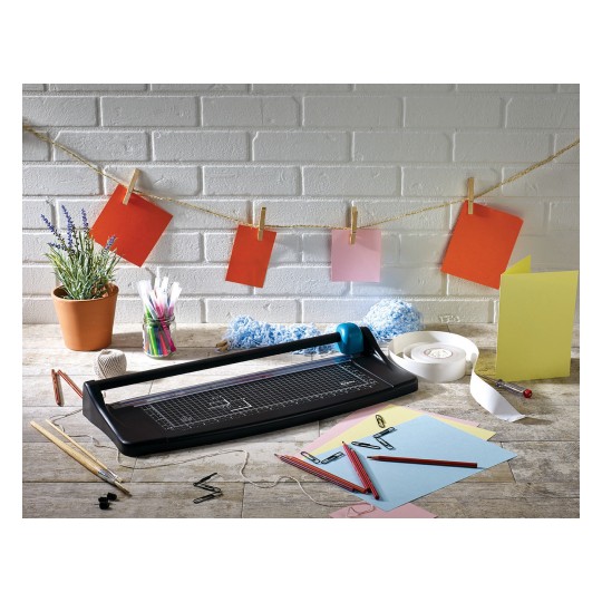 Image of a desk with a paper cutter, colorful papers, clips, and other office supplies. Background with a string from which colorful notes are hanging.