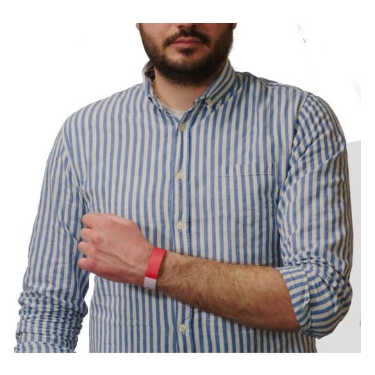 The image shows a person wearing a striped shirt with a red wristband on their arm. They are holding their arm in a way that the wristband is visible, and the background is plain white.
