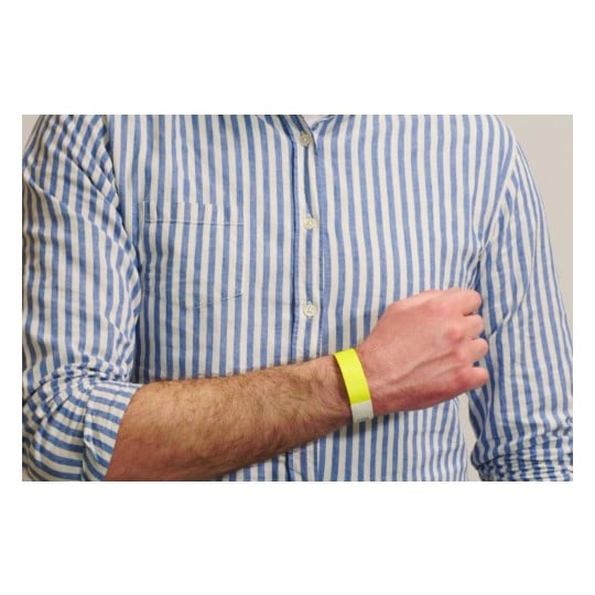 The image shows a close-up of a person's arm wearing a yellow wristband. The person is dressed in a blue and white striped shirt, with the arm positioned to show the wristband clearly.
