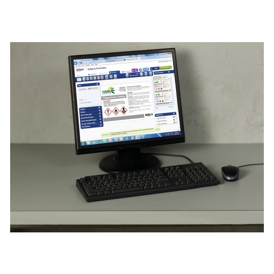 The image shows a computer monitor displaying a design and print interface for labeling products, featuring a focus on a polyurethane coating with hazard symbols and editing options. A keyboard and mouse are also visible on the desk.