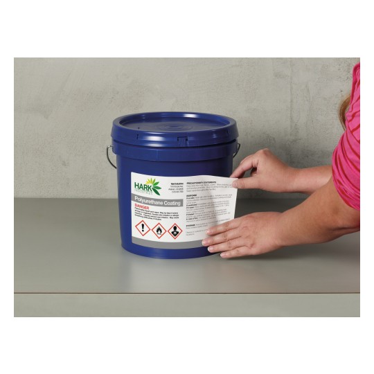 The image shows a blue bucket labeled 'Polyurethane Coating' with a danger warning. A person's hand is seen applying a precautionary label on the bucket, which includes information about handling and safety.