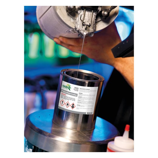 In the image, a liquid is being poured from a container. A hand holds a spray gun above a can that says 'Polyurethane Coating', with warning symbols. It looks like a paint or coating process.