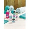 The image displays a collection of beauty and skincare products including hand wash, body lotion, face wash, and face cream, arranged beautifully on a white wooden surface with teal towels in the background.