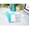 The image depicts an organized workspace with binders, folders, and labeled tabs for budgets, analysis, pricing, markets, forecast, and agenda. There are also printed documents and a computer keyboard visible.