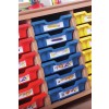 The image shows a wooden storage unit with colored bins, specifically red, blue, and yellow, containing labeled supplies such as pencils, pens, and art tools.