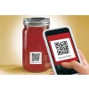 The image shows a jar with a red substance and a QR code label that says 'SCAN FOR RECIPES!' A hand holding a smartphone is positioned near the QR code.