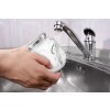 The image shows a hand holding a glass jar under running water from a kitchen faucet, while water splashes into the sink.