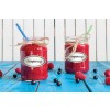 The image features two jars filled with raspberry jam, each labeled 'Raspberry'. One jar has a blue straw, while the other has a green straw. They are placed on a vibrant blue wooden surface, surrounded by fresh raspberries and blueberries.