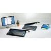The image shows a workspace with two paper trimmers, a computer displaying a webpage, a potted plant, a white mug, and a blue organizer with stationery items.