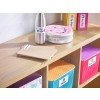 The image features a wooden shelf displaying various organized items. There's a thermos, a round lunchbox with a donut design, and colored storage bins labeled with different categories like 'Bricks' and 'Farm Toys.' There are also some notebooks placed on the shelf, adding to the organized theme.