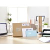 The image shows a workspace with a laptop, a large cardboard box, various letters, a cylindrical package, and an organized filing tray, all of which are labeled with addresses.