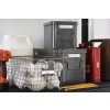 The image shows a storage area with labeled gray boxes, a wire basket filled with light bulbs, a power tool, and various containers.