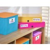 The image shows a collection of colorful storage boxes labeled with different names, including 'Bricks', 'Key Stage 1', and 'Key Stage 2'. They are placed on a wooden shelf with sunlight illuminating the scene.