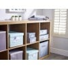 The image features a wooden shelf with various storage boxes and a small planter. The top shelf contains decorative items including potted plants and file organizers. The lower shelves hold labeled boxes in pastel colors, like blue and grey, organized for storage purposes.
