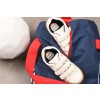 The image shows a white soccer ball, a pair of white athletic shoes with velcro straps, and a blue backpack with red details.