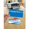 The image features a printer with travel-themed business cards being printed. The cards display the name 'Seven Seas Voyages' and a message addressed to 'Mrs. Clarke' with travel information. The design is colorful, featuring blue and white waves.
