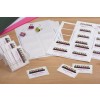 The image shows a collection of name badges and business cards arranged on a wooden surface. Various colored paper clips are present, along with sheets of adhesive name badge labels. The badges display names and roles related to a seminar or event, suggesting an organizational or professional context.